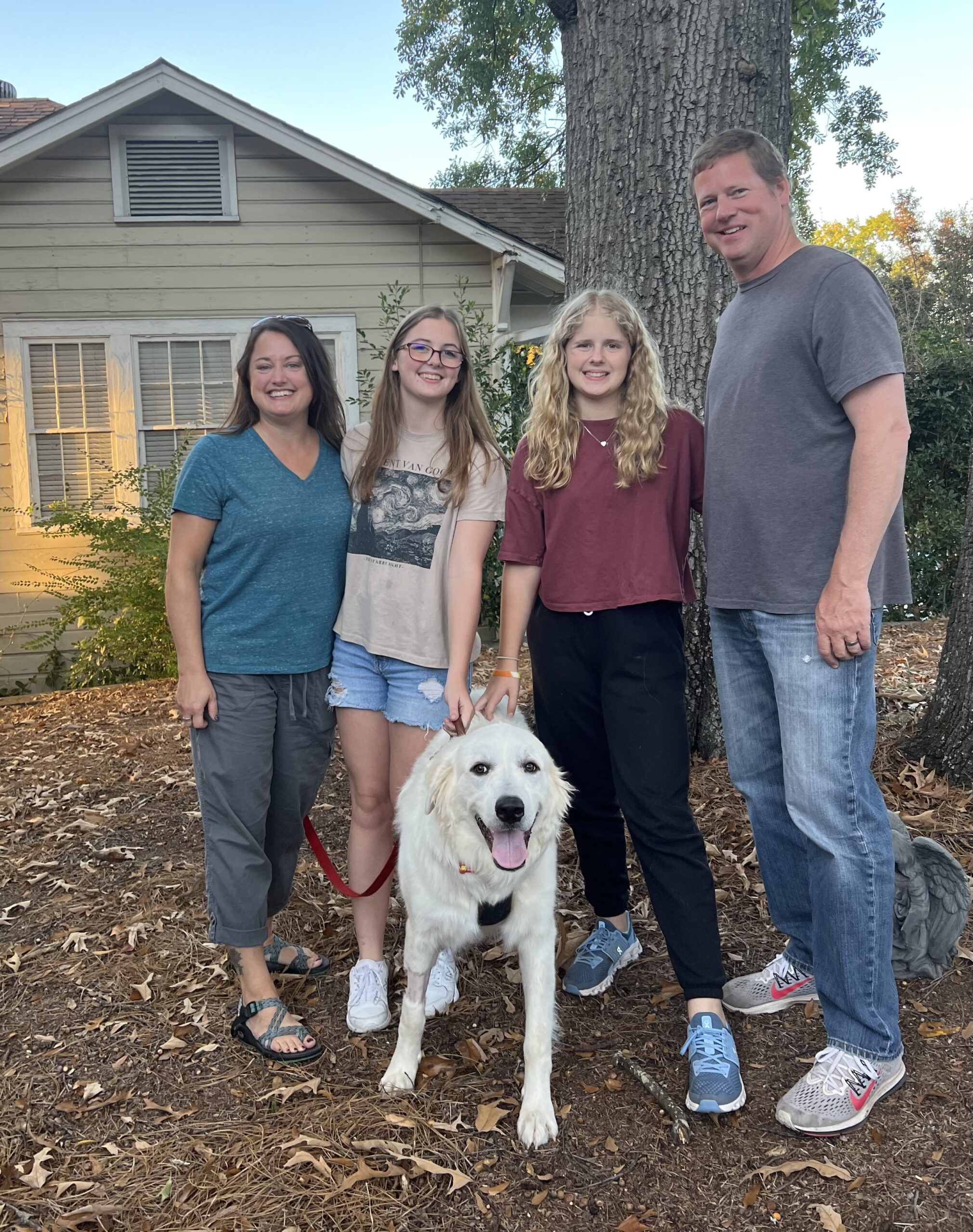 Family of four standing in front of a tree with golden retriever on leash