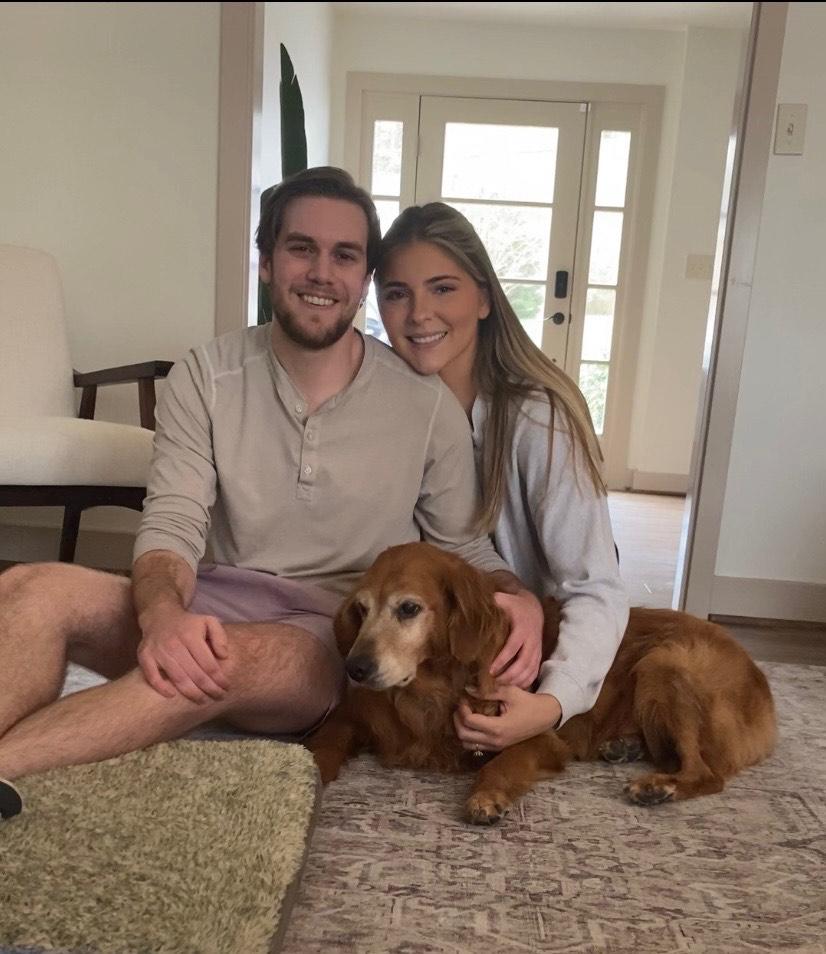 Couple sitting on the floor with a golden retriever