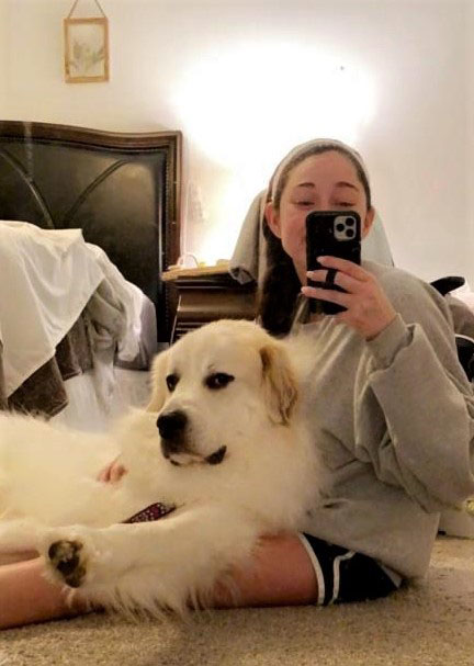 Girl taking a mirror selfie sitting on the floor with golden retriever in lap