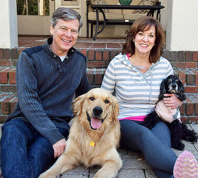 Couple sitting with a golden retriever and smaller, older black dog