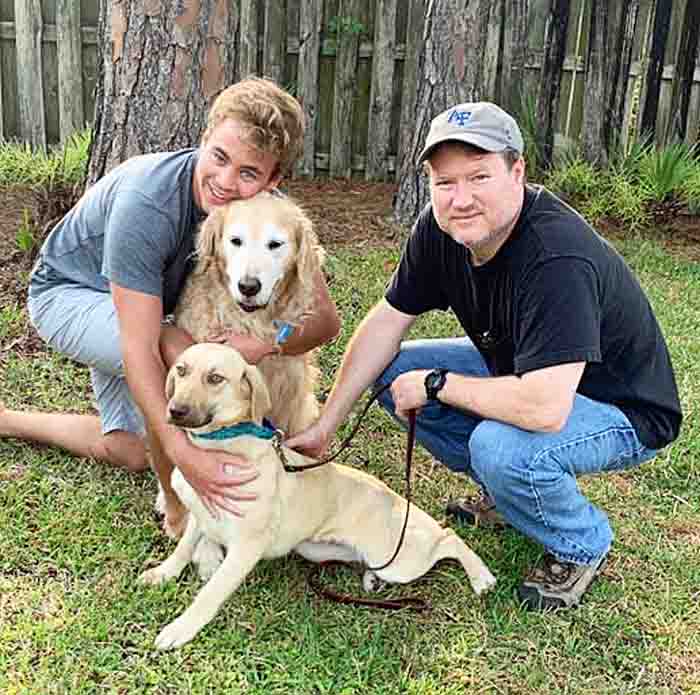 Father and son with golden retriever and another dog
